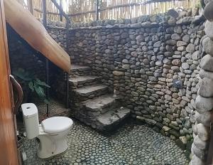 a bathroom with a stone wall and a toilet at SUMATRA ECORESORT in Bukittinggi