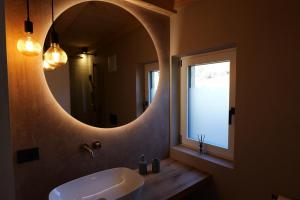 a bathroom with a round mirror and a sink at Praterhof Chalet in Südtirol - Natur, Ruhe & Bergblick in Bressanone +36 photos