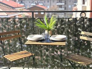 a table on a balcony with plates and a plant at Hope Casa Vacanza Bareggio in Bareggio