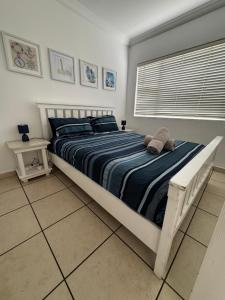 a bedroom with a bed with a blue striped comforter at Mangrove Beach Estate Boboyi in Port Shepstone +22 photos