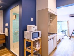 a kitchen with blue walls and a microwave on a shelf at ランズコンドホテル宮古島 in Miyakojima