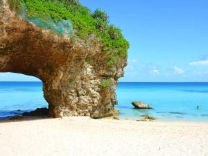 a beach with a large cliff and the ocean at ランズコンドホテル宮古島 in Miyakojima