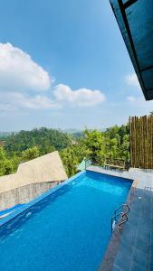 a large blue swimming pool with a view of trees at Mountain View A frame Pool Villa in Meppādi