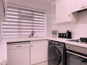 a kitchen with white cabinets and a washing machine at Wildoaks in Northwood