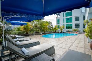 a pool with lounge chairs and a blue umbrella at Mondial Hotel Hue in Hue