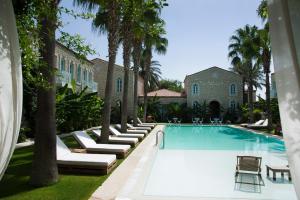 a swimming pool with lounge chairs and a house at Manastir Alacati Hotel in Alaçatı