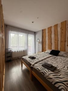a bedroom with a large bed with a wooden wall at visitDINAMO in Kandava
