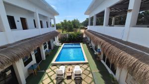 an external view of a building with a swimming pool and chairs at Camotes Hostel Resort Fan Rooms in San Francisco