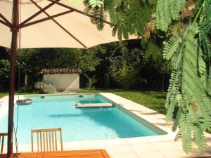 a swimming pool with an umbrella and two chairs at Gîte les Peyrets in Montech