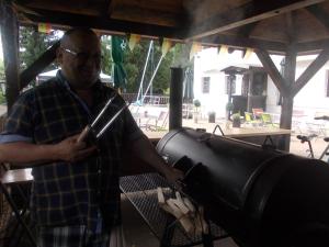 a man standing next to a grill with a pan at Pension U Jelinka in Nové Hamry