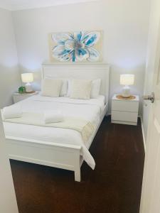 a white bed with two night stands and two lamps at Bronte Lodge, Wine Country Farm Stay Hunter Valley with Games Room, Close to Town in Greta Main