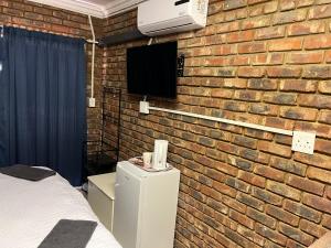 a bedroom with a brick wall with a bed and a tv at 5 Moepel in Potchefstroom