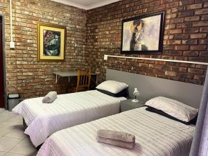 a bedroom with two beds and a brick wall at 5 Moepel in Potchefstroom