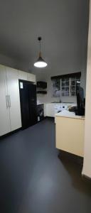 a kitchen with white cabinets and a black refrigerator at Halford Backpackers, Durban in Durban