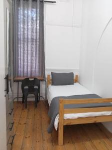 a bedroom with two beds and a chair and a window at Halford Backpackers, Durban in Durban
