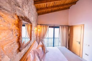 a bedroom with a stone wall with a bed and a window at Atrium Suites Taş Konak in Urla