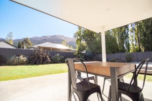 a wooden table and chairs under a white umbrella at Hāwea Home Haven in Lake Hāwea