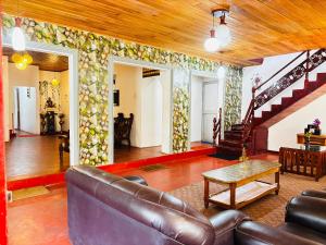 a living room with a leather couch and a staircase at Shellys Cottage Nuwara Eliya in Nuwara Eliya