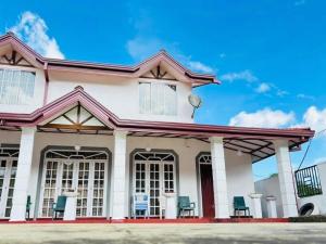 a white house with chairs in front of it at Shellys Cottage Nuwara Eliya in Nuwara Eliya