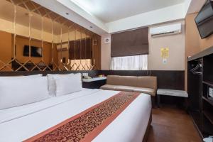 ein Hotelzimmer mit einem großen Bett und einem Fernseher in der Unterkunft Favor Hotel Makassar City Center By LIFE in Makassar