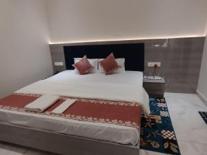 a bedroom with a large white bed with red pillows at RK Residency in Ayodhya