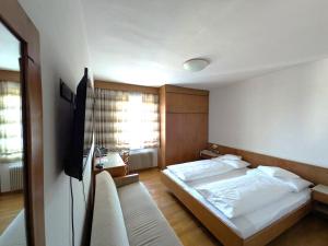 a bedroom with two beds and a flat screen tv at Hotel Gasthof Stern in Nova Ponente