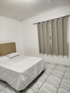 a white bedroom with a bed and a window at Casa com piscina Ana Eliza in Cambé +57 photos