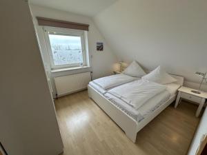 a bedroom with a white bed and a window at Fehmarn 17-1 in Fehmarn