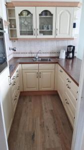 a kitchen with white cabinets and a wooden floor at Strandhotel Wohnung 31 in Dahme +14 photos