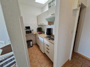 a small kitchen with white cabinets and appliances at Feriengarten Dahme W 8 in Dahme