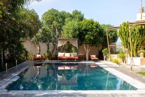 a swimming pool in a backyard with chairs and trees at Smala Beldi Guest House in Essaouira