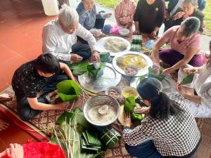 a group of people sitting around a table with food at Đức Tới Farmstay in Ho Tô