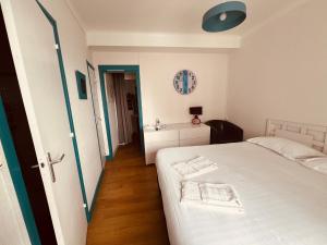 a bedroom with a white bed and a bathroom at Hotel Le Crist Al, Front de mer, chambres climatisées et son studio non climatisé, proche du centre ville in Saint-Georges-de-Didonne