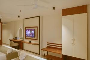 a bedroom with a bed and a desk and a tv at Len R Inn in Belgaum