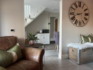 a living room with a couch and a clock on the wall at Altonhill Cottage - room only in Nairn +6 photos