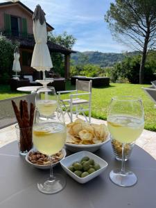 a table with two glasses of white wine and snacks at Villa delle rose Brisighella in Brisighella