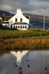 Hotel Eilean Iarmain في Isleornsay: مبنى ابيض وانعكاسه في جسم الماء