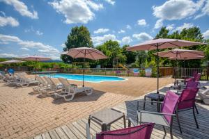 a group of chairs and umbrellas next to a pool at Camping Le Bosquet in Domme