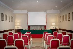 a conference room with red chairs and a screen at Hotel Athena in Siena
