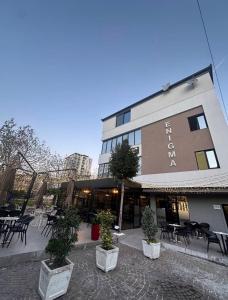 a building with tables and chairs in front of it at Enigma Rooms in Lezhë