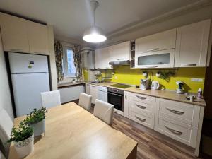 a kitchen with white cabinets and a wooden table at Middeltown rose in Alba Iulia