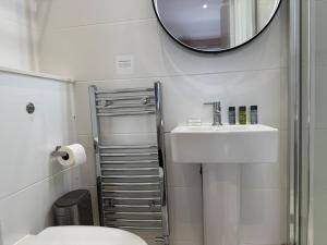 a bathroom with a toilet and a sink and a mirror at The Applewood Regency in Southwell