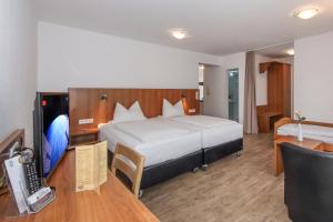 Schlafzimmer mit einem Bett und einem Schreibtisch mit einem Telefon in der Unterkunft Aalener Ratshotel - City Aparthotel Aalen Renovierung 2023 bis 2024 in Aalen