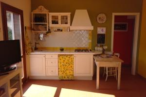 カスタニェート・カルドゥッチにあるGuardando L'Orizzonteの白いキャビネットと小さなテーブル付きのキッチンが備わります。