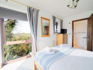 a bedroom with a bed and a large window at Sycamore in Penpillick