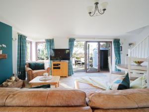 a living room with two couches and a tv at Sycamore in Penpillick