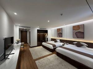a hotel room with two beds and a television at Osea Hotel in Sihanoukville