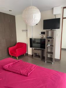 a living room with a red bed and a flat screen tv at El Sol de Simbal in Trujillo