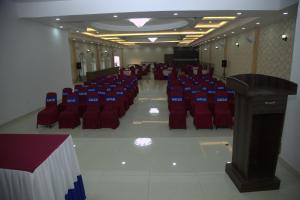 a room with red chairs and a podium and a stage at Gautam Buddha International Hotel Ltd in Gautam Buddha International Airport
