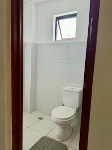 a bathroom with a white toilet and a window at Henritz Apartelle in Sogod +8 photos